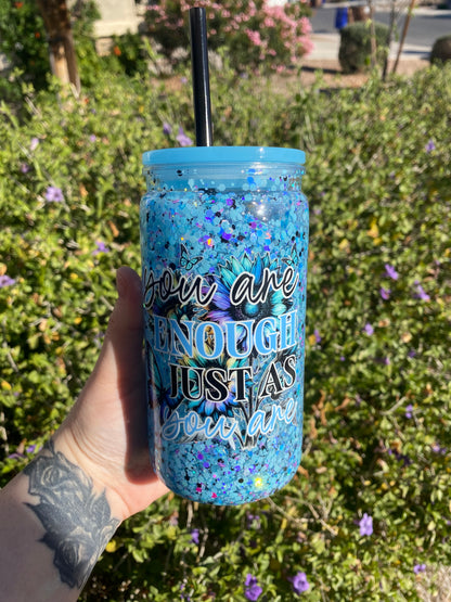 Blue glitter snow globe tumbler with the design that says you are enough just as you are with flowers and a butterflies